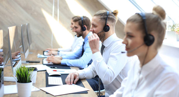istock Portrait of call center worker accompanied by his team. Smiling customer support operator at work. 1157755384