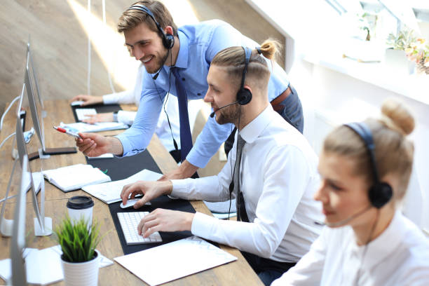 istock Phone operator working at call centre office helping hiss colleague. 1157755430