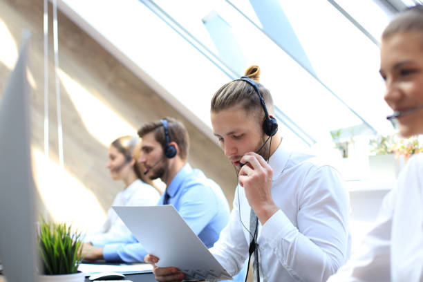istock Portrait of call center worker accompanied by his team. Smiling customer support operator at work. 1157755618