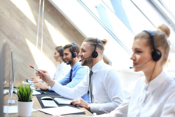istock Portrait of call center worker accompanied by his team. Smiling customer support operator at work. 1157755749