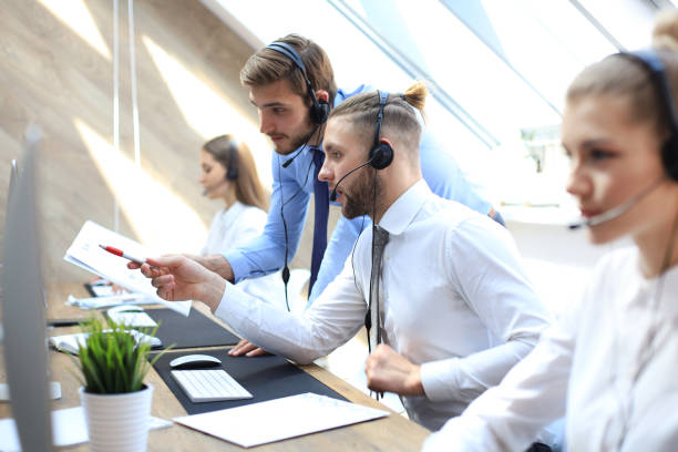istock Phone operator working at call centre office helping hiss colleague. 1157755757