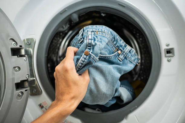 putting jeans into the washing machine - lavar roupa imagens e fotografias de stock