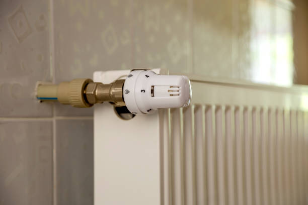 istock Heating radiator with thermostat valve on light wall tiles copy space background. Comfortable warm home interior, climate control, money saving concept. 1157766453