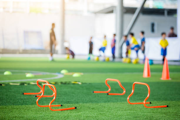 istock orange hurdles on green artificial turf with blurry coach and kid soccer are training 1157767314