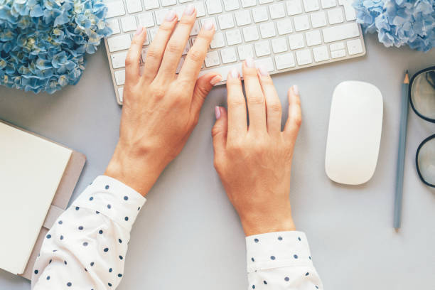 op view of hands in a polka-dot shirt typing on a computer keyboard