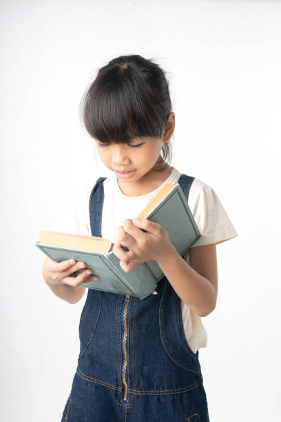 istock Young Asian girl student reading book isolated on white background 1157772680