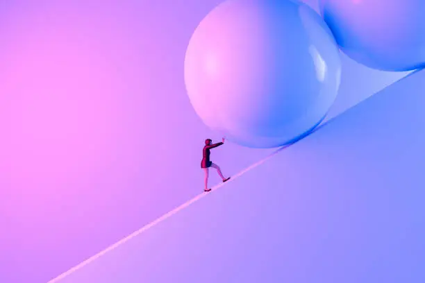 Photo of Business Woman pushing large stone uphill