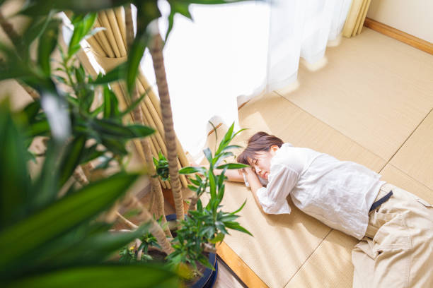 junge frau schläft auf tatami-matte durch fenster - tatami matte stock-fotos und bilder