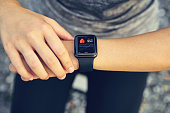 Young woman checking the sports watch measuring heart rate and performance after running.