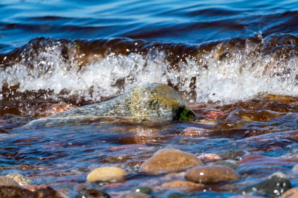 Seawater and waves flooding coloured pebbles on the beach