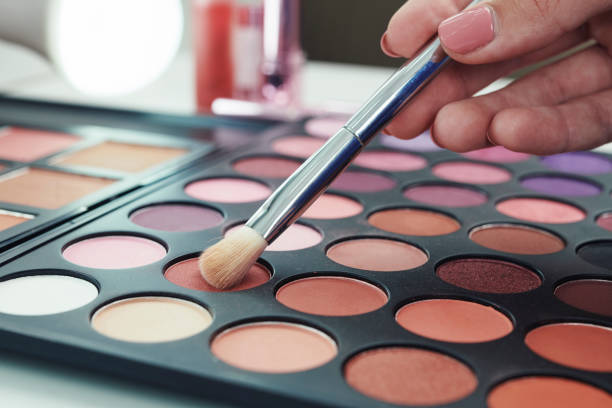 Woman choosing brown shadow Close-up image of woman using choosing brown color to from eyeshadow palette make up palette photos stock pictures, royalty-free photos & images