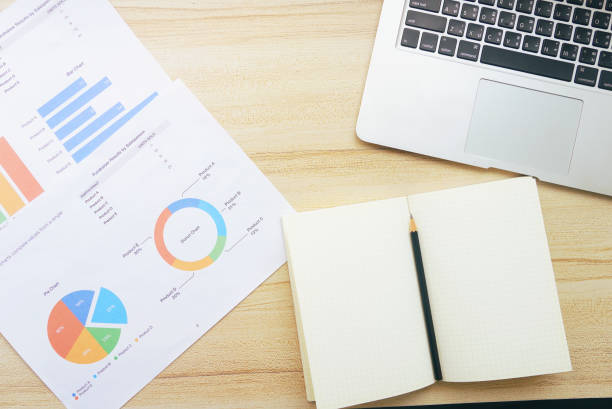 istock Top view pencil on a book with laptop and chart data paper on the table. 1157787418