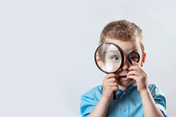 istock boy in a light t-shirt looking into a large magnifying glass 1157790398