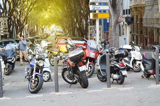Marseille, France, 12 October 2018. Numerous motorcycles and scooters are parked next to the sidewalk, autumn cityscape.