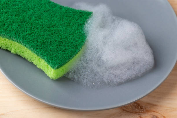 istock A hand with a green spunge washes a gray ceramic plate with detergent foam 1157798437