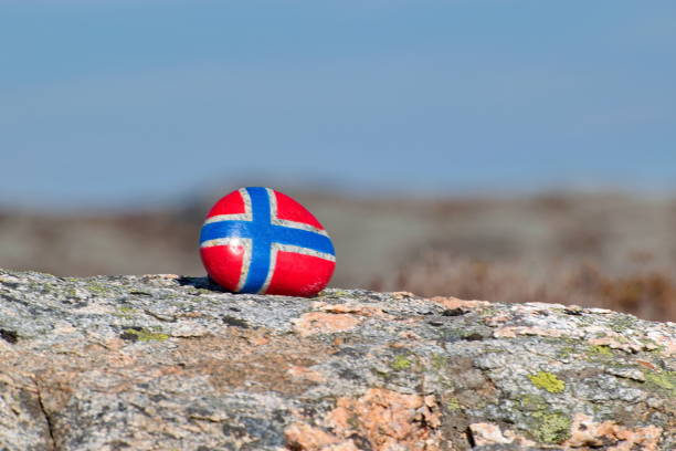 Image of the flag of Norway on a stone, between sea pebbles and seashells. Concept of Norwegian Constitution Day.  Celebrated on May 17.