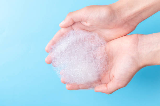 istock Two hands hold a bunch of foam while washing their face and body 1157798893