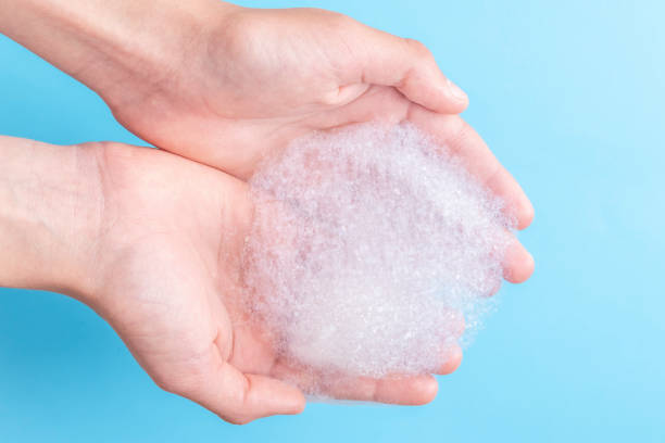 istock Two hands hold a bunch of foam while washing their face and body 1157798913