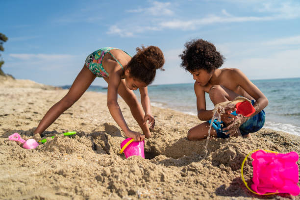 kinder spielen mit sand am strand - lifestyles child beach digging stock-fotos und bilder