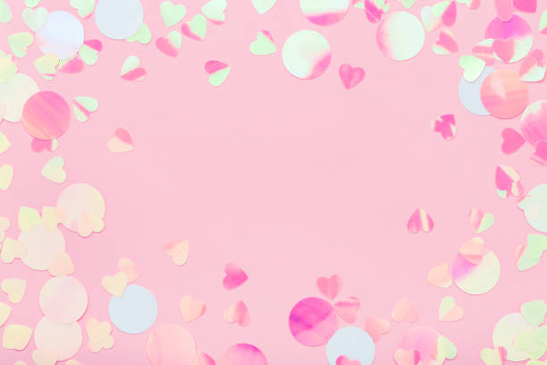 istock Festive frame of iridescent multicolored confetti sparkling on pink pastel background. 1157803192