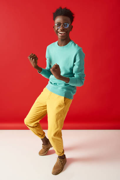 istock Positive young man in glasses is dancing on red background 1157803223