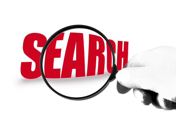 istock Gloved hand holding a magnifying glass against the word search 1157803225