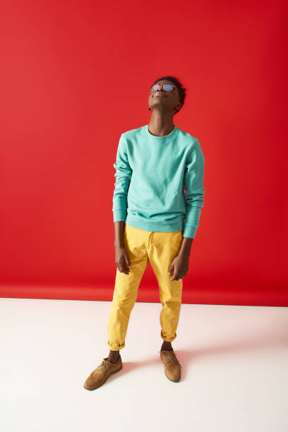 istock Young Afro American guy in glasses posing on red background 1157803226