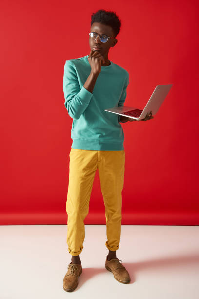 istock Young African American guy standing with laptop 1157803235