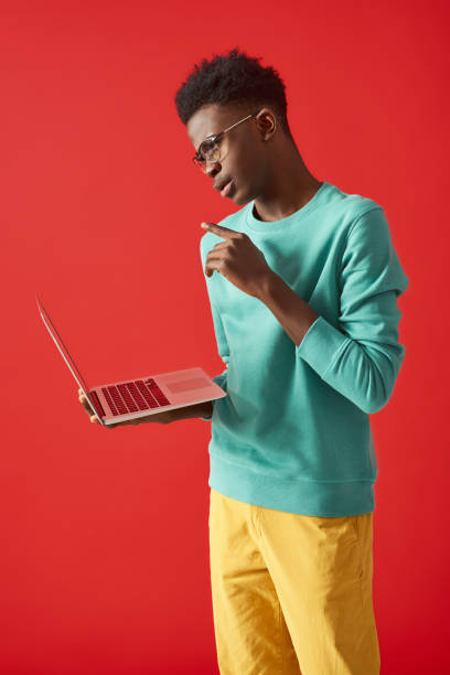 istock Young African American man standing with laptop 1157803236