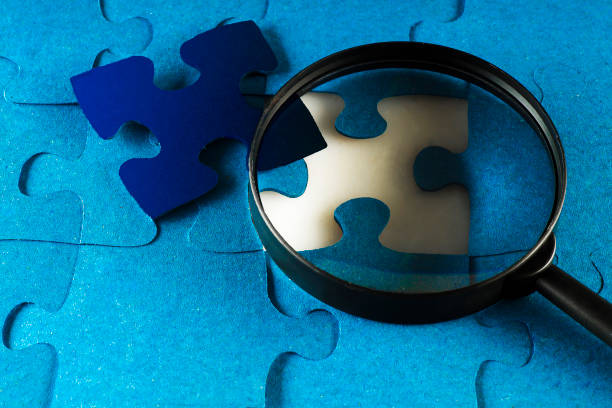 istock A magnifier on the background of a puzzle with one matching element 1157804205