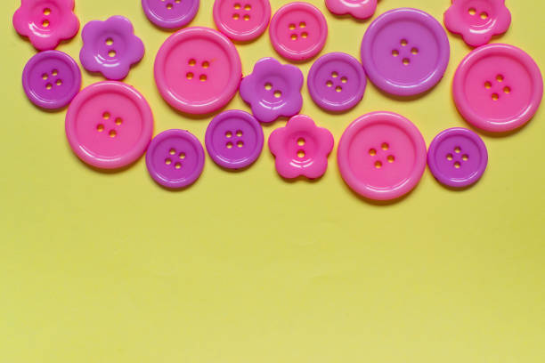 istock Various pink sewing buttons on light yellow background with place for text 1157804522