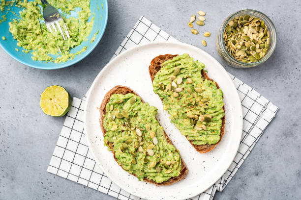 toast d'avocat sain avec des graines de citrouille - pain de seigle photos et images de collection