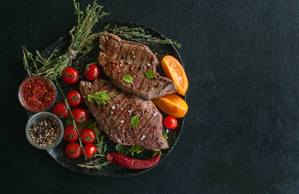 istock Grilled beef steak, greens, tomatoes and spices. Top view with copy space for text 1157806831