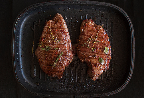 Grilled Black Angus Steak Striploin on frying cast iron Grill pan on dark background