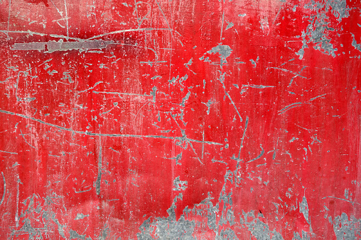 old vivid red color obsolete gate texture is peeled and full of scratches, abstract industrial background