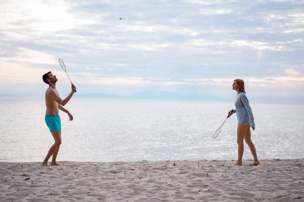 Friends playing badminton Friends are playing badminton on the sandy beach. badminton racket stock pictures, royalty-free photos & images