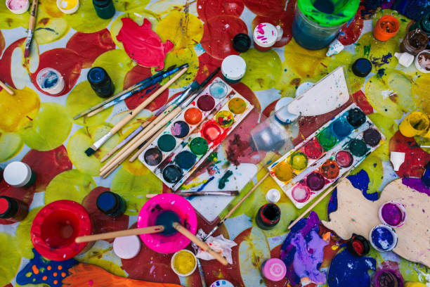 istock The process of drawing and creating creativity. A large table on which are brushes, paints, cans of water and a palette. Drawing lesson at school or creative studio. Artist tools. View from above 1157811153