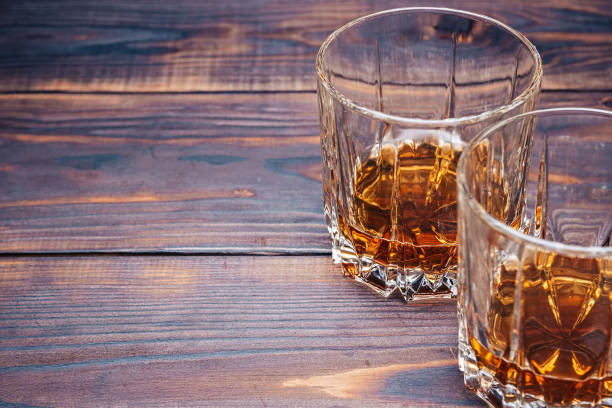 istock Two glasses of whiskey on a wooden table 1157813536