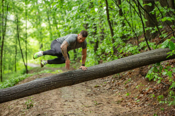 istock Flexible and Strong Mid Adult Jumping Over Tree Trunk 1157822471