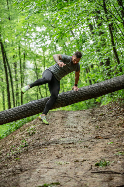 istock Flexible and Strong Mid Adult Jumping Over Tree Trunk 1157822472