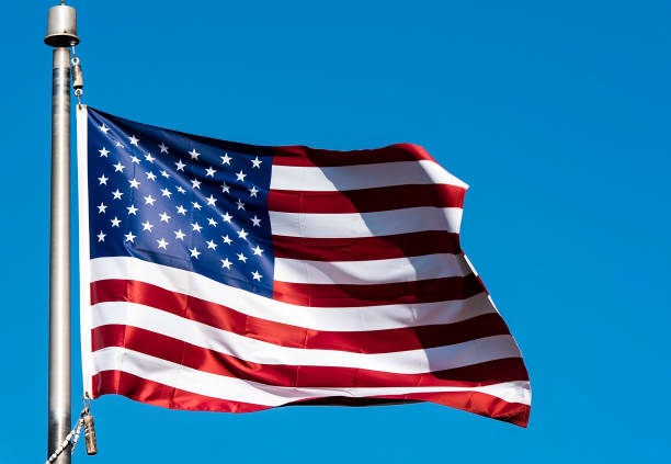 istock USA Flag and clear blue Sky as Background 1157823350