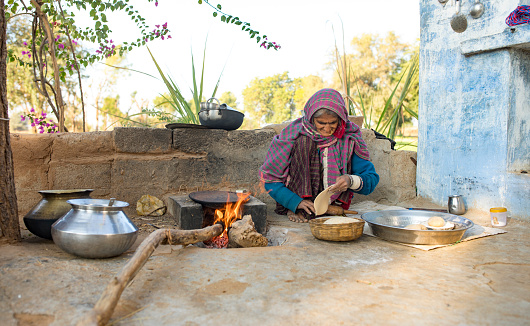 Sedua, India - January 04, 2018: indian woman cooking chapatis at outdoor kitchen of there house, Chapatis are the staple diet of all Indians, Sedua, India - January 04, 2018