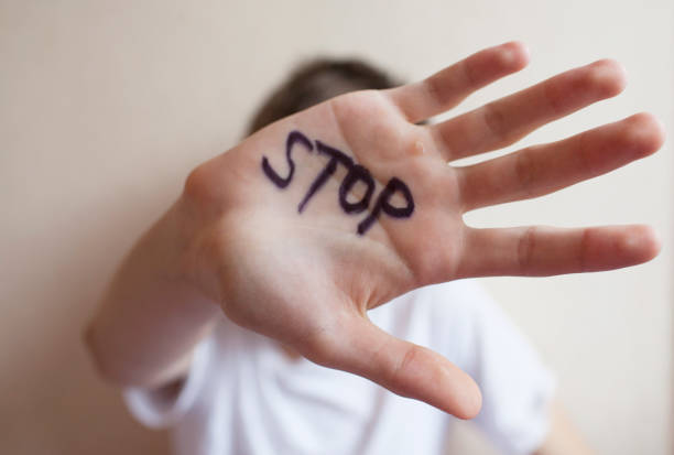 le garçon de l'adolescence se protège avec sa main dans la paume de son inscription "stop" - protective suit photos photos et images de collection