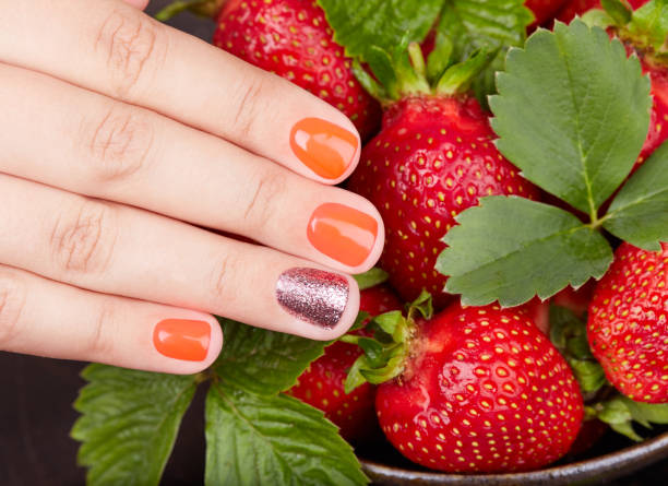 istock Hand with short manicured nails colored with red nail polish and strawberries 1157829221