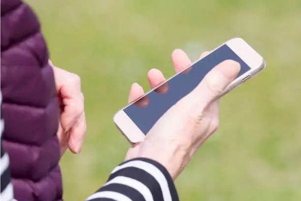 Senior elderly woman using touch screen mobile smart cell phone showing old hands uk