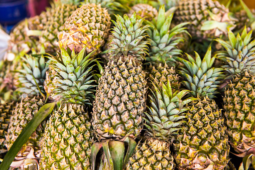 Pile of tropical fruits pineapples on market. Can be used as food background