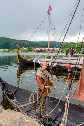 Lofotr, Norway - August 2, 2017  Man preparing Reconstructed Viking boat in the border of Innerpollen salty lake in Vestvagoy island of Lofoten archipelago. The area is a part of Lofotr Historical museum. Nordland, Northern Norway.