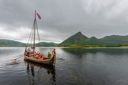 Lofotr, Norway - August 2, 2017  Departure of the Reconstructed Viking boat with tourists, in Innerpollen salty lake in Vestvagoy island of Lofoten archipelago. The area is a part of Lofotr Historical museum. Nordland, Northern Norway.