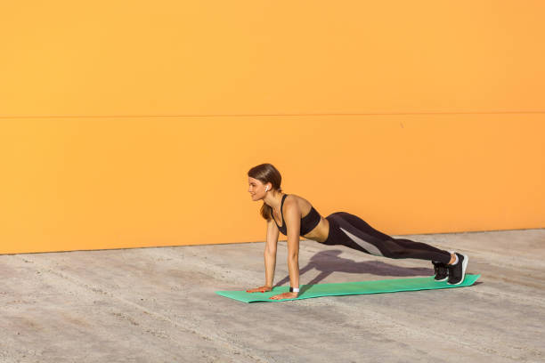 istock Young sporty woman practicing yoga, doing push ups or press ups exercise, phalankasana, plank pose, working out 1157840062