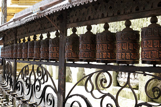 Prayer wheels Swaybunath Stupa Nepal Prayer wheels in row around wall of Swayabunath Stupa in the Kathmandu valley, Nepal. The Stupa is sacred for both Buddhists and Hindus of Nepal and dates back to the 5th Century or before.  Prayer wheels contain the mantra or prayer for the Buddha of Compassion and when turned send out prayers for peace and compassion for all beings. prayer wheel nepal kathmandu buddhism stock pictures, royalty-free photos & images